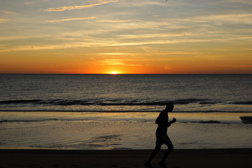 Fototapeta na wymiar Man running at the beach of Tybee Island, Georgia, USA during sunrise