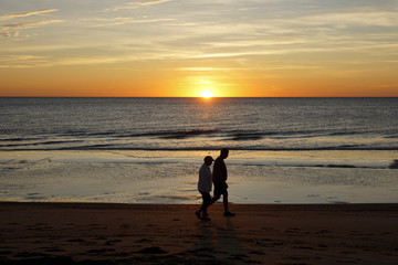 Couple walking at the beach of Tybee Island, Georgia, USA during sunrise