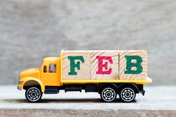 Truck hold letter block in word feb on wood background (Concept for month February)