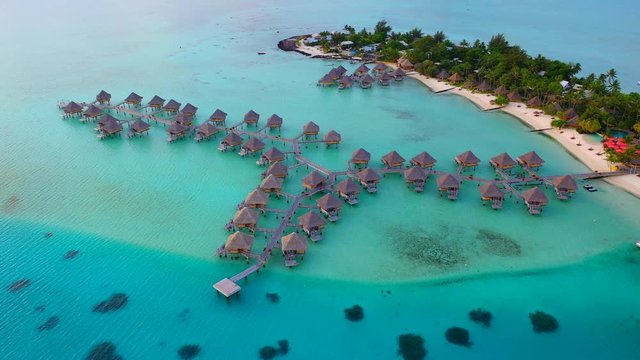 Aerial of picturesque overwater bungalows on a beautiful tropical island, drone flying backwards  - Bora Bora, French Polynesia