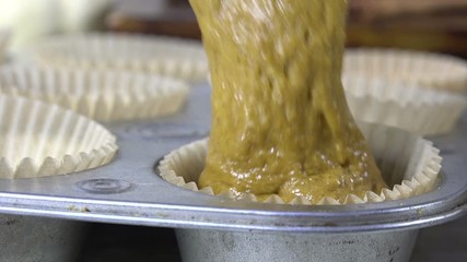 Spooning pumpkin cupcake batter into muffin tins slow motion