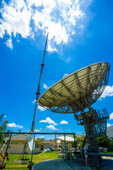 Satellite antennas and satellites. The sky is large and the clouds are white and the blue sky is the background for high telecommunication signals, wireless access devices, long distance signals, high