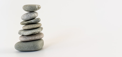 Balance concept. Stacked round beach stones on white background. Copy space.