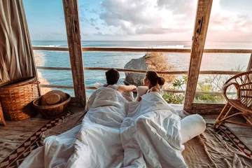 Crédence de cuisine en verre imprimé Bali Couple profitant des vacances du matin sur un bungalow sur la plage tropicale à la vue sur l& 39 océan Vacances relaxantes à Uluwatu Bali, Indonésie
