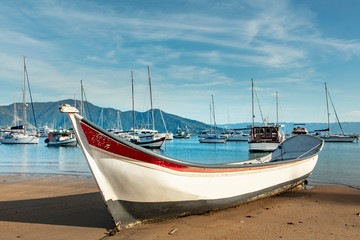 Boats in a bay on the coast of Sao Paulo on a beach in Ilhabela island with blue sea and clear sand in Brazil