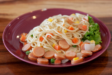 Variety colors of spaghetti for children in plate on wooden table.