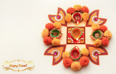 Diwali festival background content with rangoli pattern on white floor decorated with flowers and traditional clay lamps
