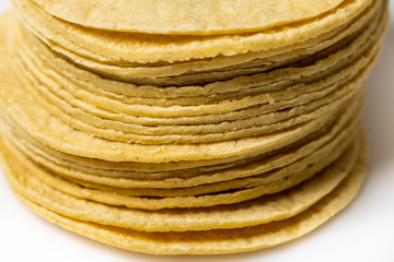 Heap of yellow corn mexican tortillas on white background