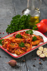 Dried tomatoes with olive oil and garlic on a wooden table. Vegetarian food.