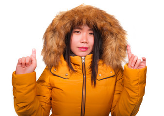 winter fashion isolated portrait of young beautiful and happy Asian Korean woman in warm yellow feather jacket with fur hood gesturing cheerful and playful smiling © TheVisualsYouNeed