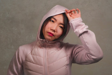 beauty and fashion style isolated portrait of young beautiful and cool Asian Chinese student woman in pink hood winter jacket isolated on grunge studio background © TheVisualsYouNeed