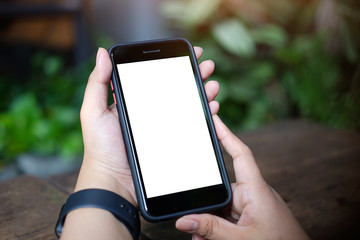 Cropped shot view of man hands holding smart phone with blank copy space screen for your text message or information content, female reading text message on cell telephone during in urban setting. 