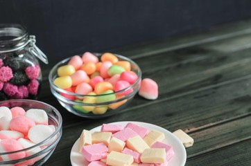 multi-colored candies in a plate, bank and bowls with copy space