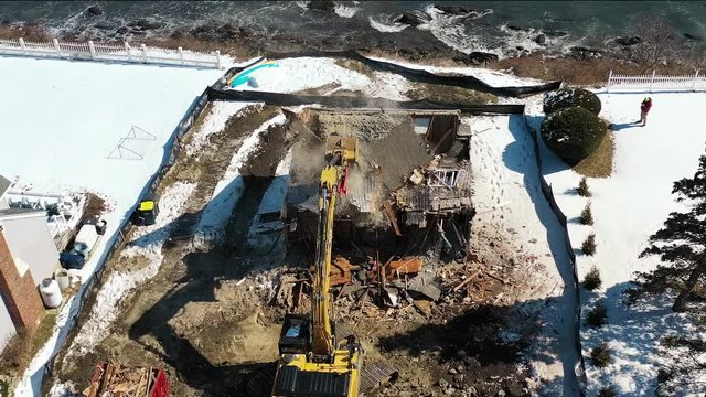 House demolition on ocean cliff as excavator topples second floor