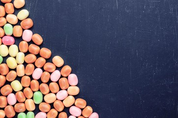 frame of multi-colored candies on a dark background with copy space