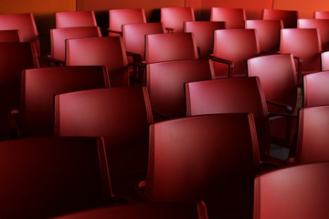 Red chairs in a large room. Rows of chairs