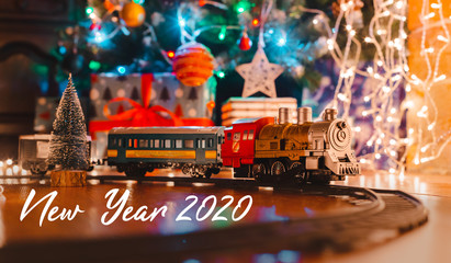 toy vintage steam locomotive on the floor under a decorated Christmas tree on a background of bokeh...