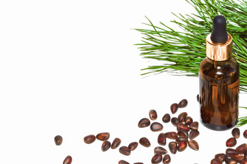 Natural pine nut oil in a bottle with a pipette. Vitamins of group B, D. Pine branch and pine nuts in skarlupe on an isolated white background.