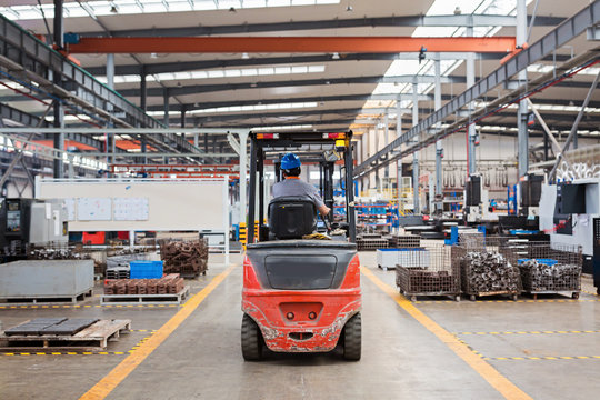 Employee working on forklift in modern warehouse. Boxes are on the shelves of the warehouse. Warehousing, machinery concept.