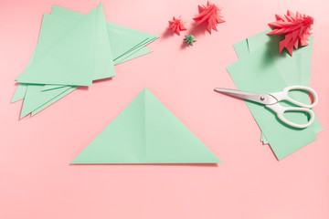 A process of making 3D fir tree from green paper on pink background. Step by step instruction, step...