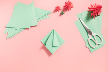 A process of making 3D fir tree from green paper on pink background. Step by step instruction, step 7. Fold right and left side to the centre line.
