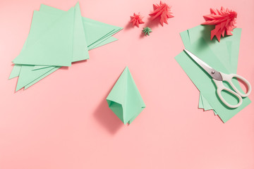 A process of making 3D fir tree from green paper on pink background. Step by step instruction, step...