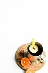 Hot flavored drink with mandarin, apple and lemon on a cork stand.