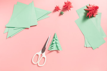 A process of making 3D fir tree from green paper on pink background. Step by step instruction, step 14. Fold each branch to get the finished product