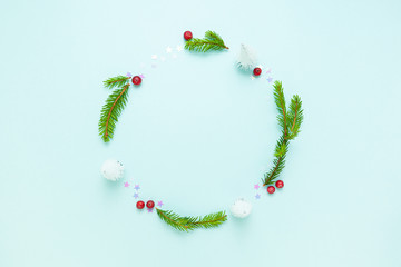 Christmas circle floral composition. Wreath of fir tree, cranberry berries and white confetti stars on blue background. Winter design. Flat lay