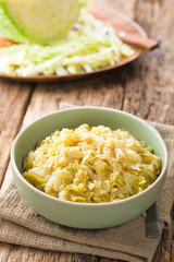 Fresh homemade braised white cabbage in bowl, raw cabbage in the back (Selective Focus, Focus one third into the cabbage)