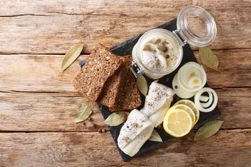 Baltic pickled herring with onions in a glass jar close-up on the table. horizontal top view
