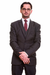 Studio shot of young businessman in suit standing