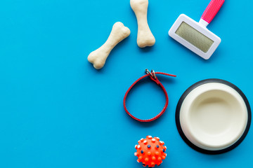 Set of treats and toys for pets with bones, collar and bowl on blue background top view frame copy space