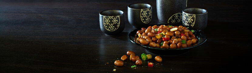 Sake Japanese whiskey in bottle and cup and Salt roasted peanuts in black dish