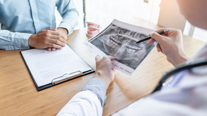 Medical team discussing, health care talking to female patient, Medical conferrence concept, doctor holding and looking at dental x-ray attending a client.