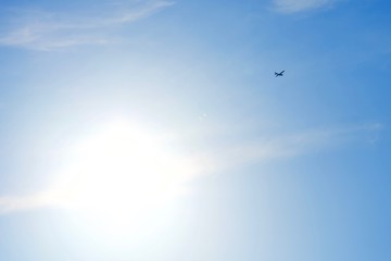太陽と空を舞う小型飛行機のシルエット