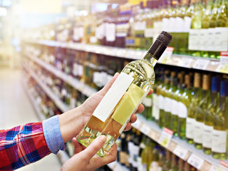 Woman with bottle of wine in store