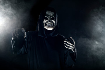 Scary looking grim reaper ghost coming out of the foggy mist.  The haunting creepy demon depicts...