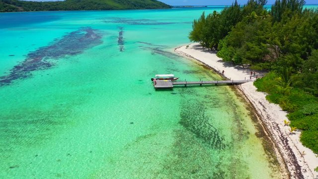 Aerial of a dock on a stunning tropical island, drone flying forward then tilting down and descending over the dock  - Bora Bora, French Polynesia