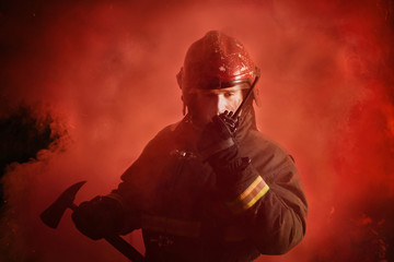 Fototapeta na wymiar Portrait of firefighter in uniform on dark red background