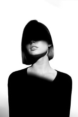 Fototapeta premium Fashionable beauty portrait. Black silhouette on white background. Girl with a spot of light on her face. 