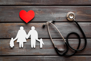 Family health care concept. Heart icon and stethoscope on dark wooden background top view