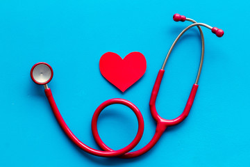 Health care concept. Heart icon and stethoscope on blue background top view