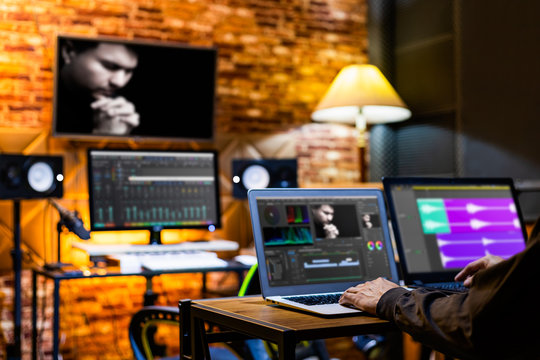 professional director, editor, producer editing movie footage and music score track on computer in digital editing, post production, broadcasting studio
