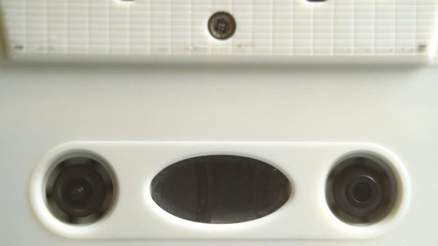Audio Cassette in Tape Recorder Rewind. Vintage tape recorder Rewind the tape inserted therein. Close-Up. Tape with blank label in use sound recording in cassette player.