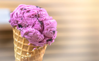 Cherry ice-cream and waffle cone with blurry wood wall background. Free copy space for text on right. 