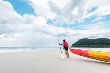 Obraz na płótnie Canvas young man carrying kayak on sand beach to the sea
