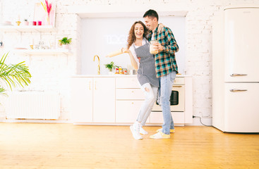 Fototapeta na wymiar Happy beautiful young couple have fun in the kitchen, dancing, cuddling, cooking food together