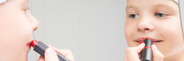 close-up, a girl looks in the mirror and paints her lips with red lipstick