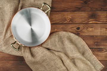 Copper pot on the dark wooden table, top view